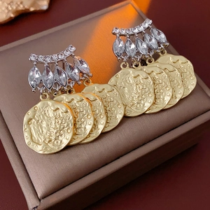 Macro shot of vintage earrings with silver rhinestone studs and gold relief coins