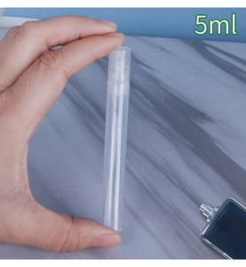 Detailed view of hand holding a slim 5ml clear plastic perfume atomizer spray bottle