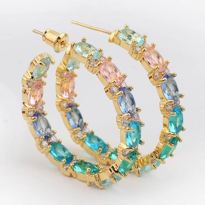 Detailed macro view of colorful oval-cut gemstones set in gold-plated hoop earrings