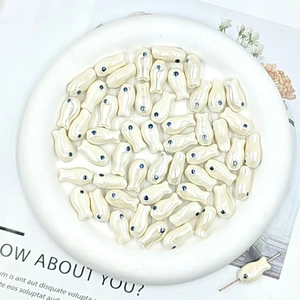 Macro shot of white ceramic fish beads with blue eyes and pearl luster for jewelry DIY