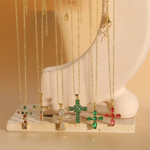 Vintage gold cross necklaces with colorful zircon stones on elegant stone display