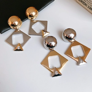 Detail of geometric silver needle earrings featuring gold and silver tones with rhinestones