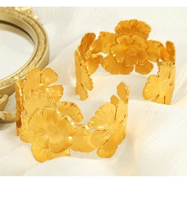 Macro detail of gold camellia flower cuff bracelets with brushed metal texture and petals
