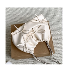 Detail view of cream white pleated PU leather bag with silver chain and bow decorations