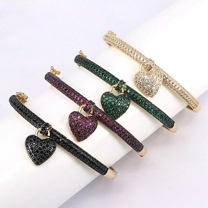 Detailed close-up of four colorful heart charms with pave-set cubic zirconia on gold bangles