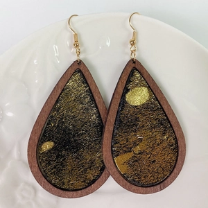Macro detail of teardrop earrings with wood frame and gold foil texture on ceramic