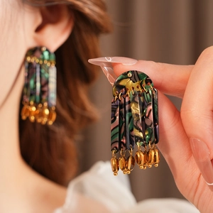 Detail shot of vintage bohemian shell pendant earrings with resin patterns and gold beads