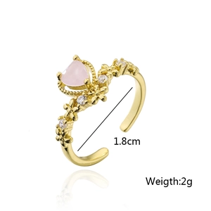 Detail view of gold open ring featuring pink heart stone and white zircon details