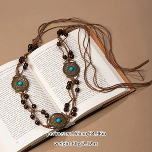 Detail of woven rope belt with turquoise bronze medallions on vintage book pages