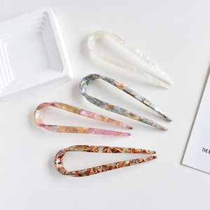 Flat lay of four tortoiseshell acetate U-shaped hair pins in various marbled colors