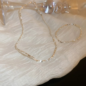 Detailed view of silver irregular cube bead necklace and bracelet set on textured fabric