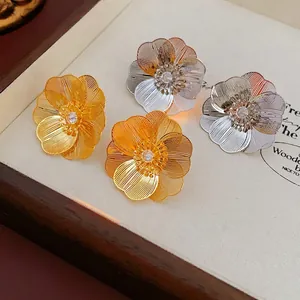 Elegant gold and silver hollow flower stud earrings with central zircon in a tray