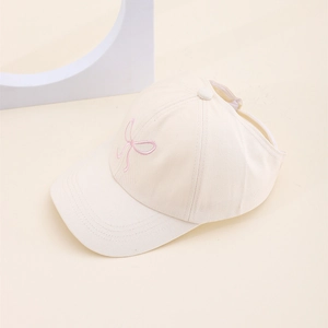 Gros plan sur la visière beige avec broderie nœud rose et design ouvert pour filles