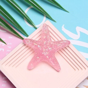 Accessorio a stella marina in resina rosa con paillettes su una base testurizzata