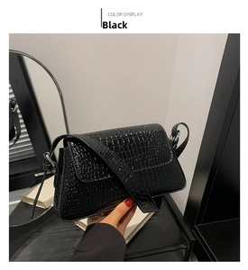 Detail of black faux crocodile pattern texture on a rectangular flap shoulder handbag