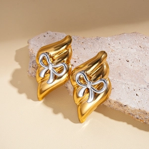 Détail de boucles d'oreilles dorées vintage avec nœud argenté sur support en pierre
