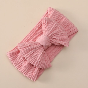 Detailed view of pink ribbed knit texture on a stretchy nylon infant bow headband