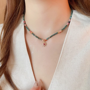 Détail du collier pendentif soleil avec pierres naturelles vertes et roses sur mannequin