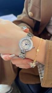 Gros plan d'une montre en acier argenté avec lunette sertie de diamants et cadran en nacre