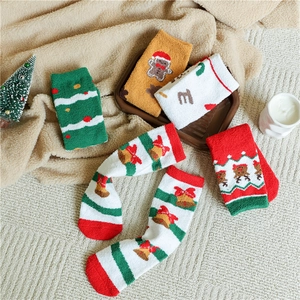 Detail view of plush Christmas coral fleece socks with festive reindeer and Santa patterns