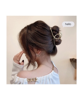 Detail view of a gold twisted metal hair claw clip styled on an elegant bun