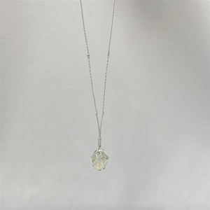 Détail du filet en cordon gris tressé autour d'un pendentif en cristal jaune brut naturel