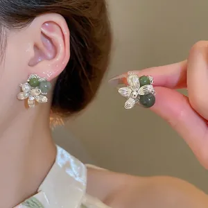 Elegant silver flower earrings with green agate and pearls worn on a model's ear