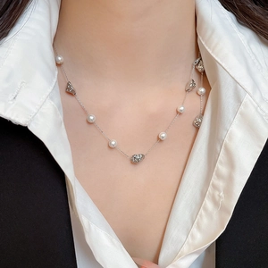 Close-up of pearl and hammered silver metal necklace on neck with elegant styling