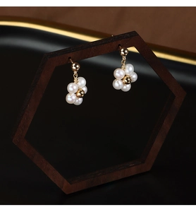 Detailed view of flower-shaped freshwater pearl earrings on a dark wooden display stand