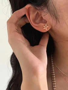 Close-up of rose gold flower stud earrings with dark gemstone worn by model