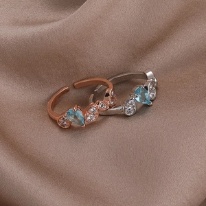 Detailed view of pear-cut blue gemstone rings in rose gold and silver on silk
