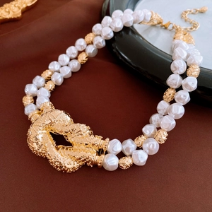 Close-up of vintage double-layer baroque pearl necklace with a large golden knot buckle