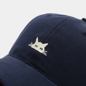 Detailed close-up of white kitten embroidery on navy blue cotton baseball cap