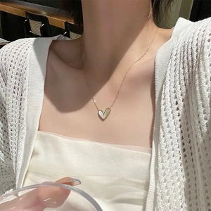 Elegant gold heart pendant necklace with white mother of pearl inlay worn by a model