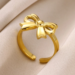 Macro shot of gold bow open ring on beige silk background with adjustable band detail