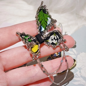 Broche papillon argentée avec de vraies fleurs séchées et fine chaîne pendante