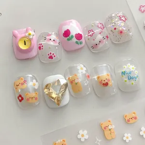 Detailed macro view of 3D bow nail stickers with pink cat and teddy bear patterns