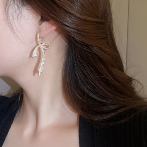 Close-up of elegant gold bow earrings with sparkling cubic zirconia on a model