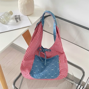 Detail of red and white checkered fabric bag with blue pocket and bow embroidery