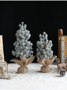 Detail of mini flocked snow Christmas trees with pine cones and burlap wrapped bases