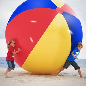 Giant colorful inflatable PVC beach ball shown with children for scale on sunny sand