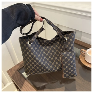 Detail der braunen Tragetasche mit Kettenmuster und passender Tasche auf einem Glastisch