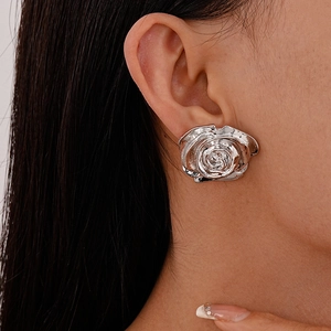 Détail d'une grande boucle d'oreille rose 3D argentée au fini métallique sur modèle
