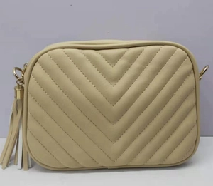 Dettaglio della borsa fotografica trapuntata beige con cuciture a V e nappa decorativa