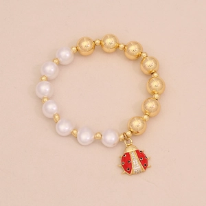 Detail of beaded bracelet with pearls, gold beads and a red ladybug charm pendant