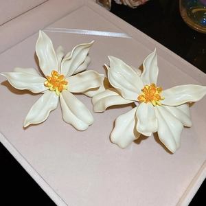 Macro shot of white acrylic flower earrings with orange beads in a pink gift box