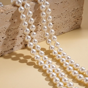 Baroque multi-layer pearl necklace on beige travertine stone with elegant glossy finish