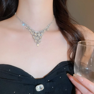 Macro shot of silver V-shaped fringe necklace with inlaid crystals on a model wearing black