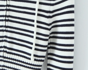 Detail des schwarz-weiß gestreiften Strickstoffs mit weißem Kordelzug und Reißverschluss