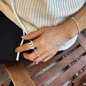 Detail of irregular wave-shaped silver ring and thin chain bracelet on hand